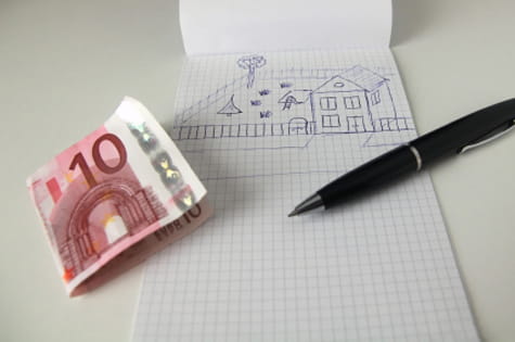 Billete de 10 euros y cuaderno con dibujo de casa
