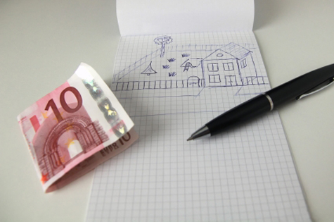 Billete de 10 euros y cuaderno con dibujo de casa
